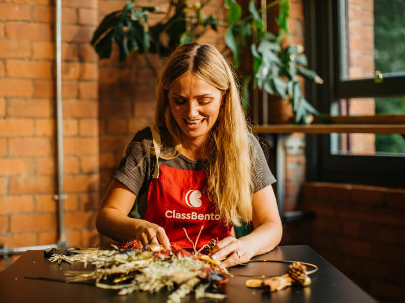A woman smiling whilst making a DIY Christmas wreath